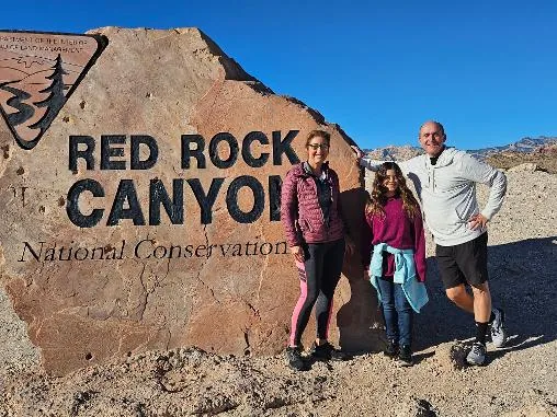 Three guests posing at the Red Rock Canyon National Conservation Area entrance sign
