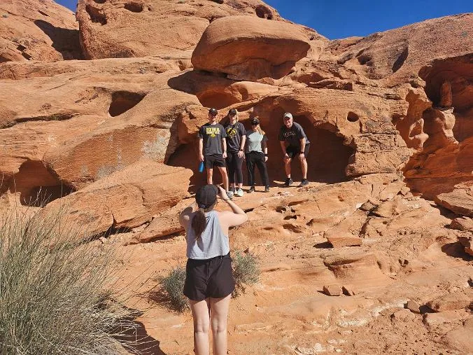 A group of guests lining up for a photo on the red sandstone during a Valley of Fire tour
